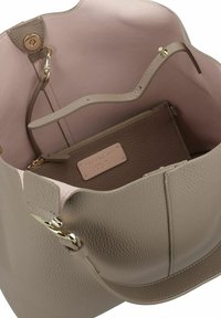 Beige leren handtas met een gestructureerd oppervlak en gouden hardware, open bovenkant die de roze voering binnenin toont en een ritsvak met merkembleem binnenin.
