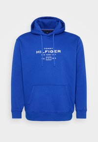 Blauwe hoodie van zachte stof met een kangoeroezak, trekkoordcapuchon en een wit gedrukt logo op de voorkant.