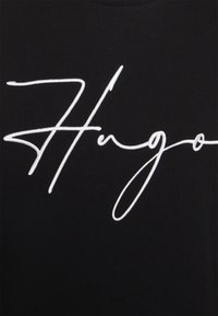 Schwarzes T-Shirt mit großem, weißem, gesticktem Schriftzug "Hugo." Leicht strukturierter Stoff mit glatter Oberfläche. Lässiges Design.