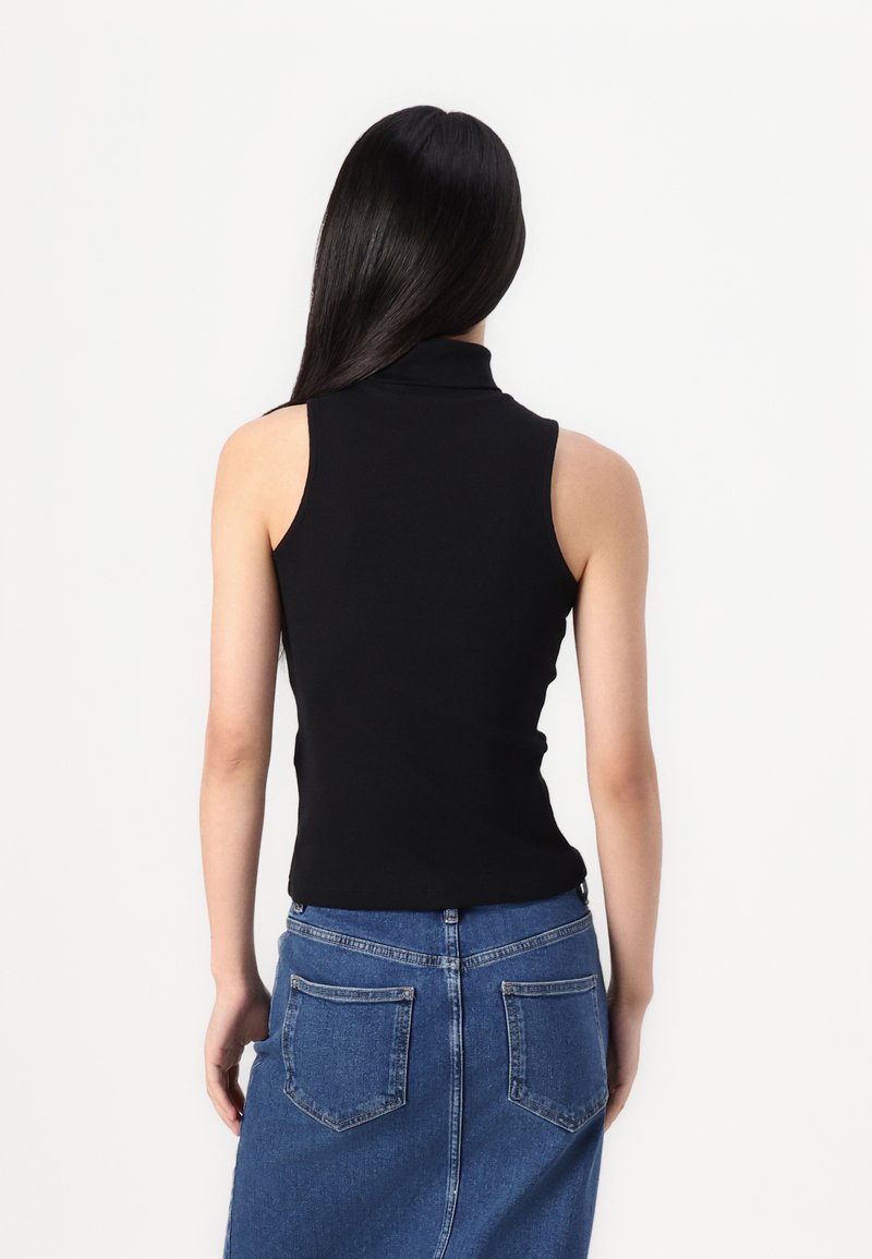 Top nero senza maniche con colletto alto, design aderente; indossato con una gonna di denim blu. Texture liscia dallo stile minimalista.