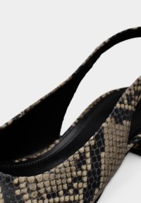 Pantof slingback cu imprimeu de șarpe, în nuanțe de negru și bej, cu textura netedă și design cu vârf decupat, având o siluetă elegantă și bretele subțiri.