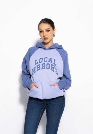 Jasnoniebieska bluza z kapturem z ciemnoniebieskimi akcentami, z kieszenią typu kangur i napisem "LOCAL HEROES" na klatce piersiowej. Miękka tkanina i luźny krój.