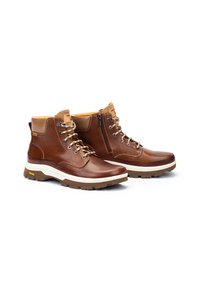 Bottines en cuir marron avec un col rembourré, dotées de lacets et d'une fermeture éclair sur le côté, ainsi qu'une semelle intermédiaire blanche et une semelle extérieure texturée marron.