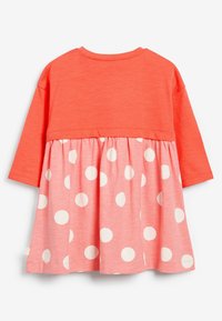 Robe longue corail à manches longues avec une jupe à pois roses froncée. Tissu lisse, coupe régulière, col rond et haut contrasté.