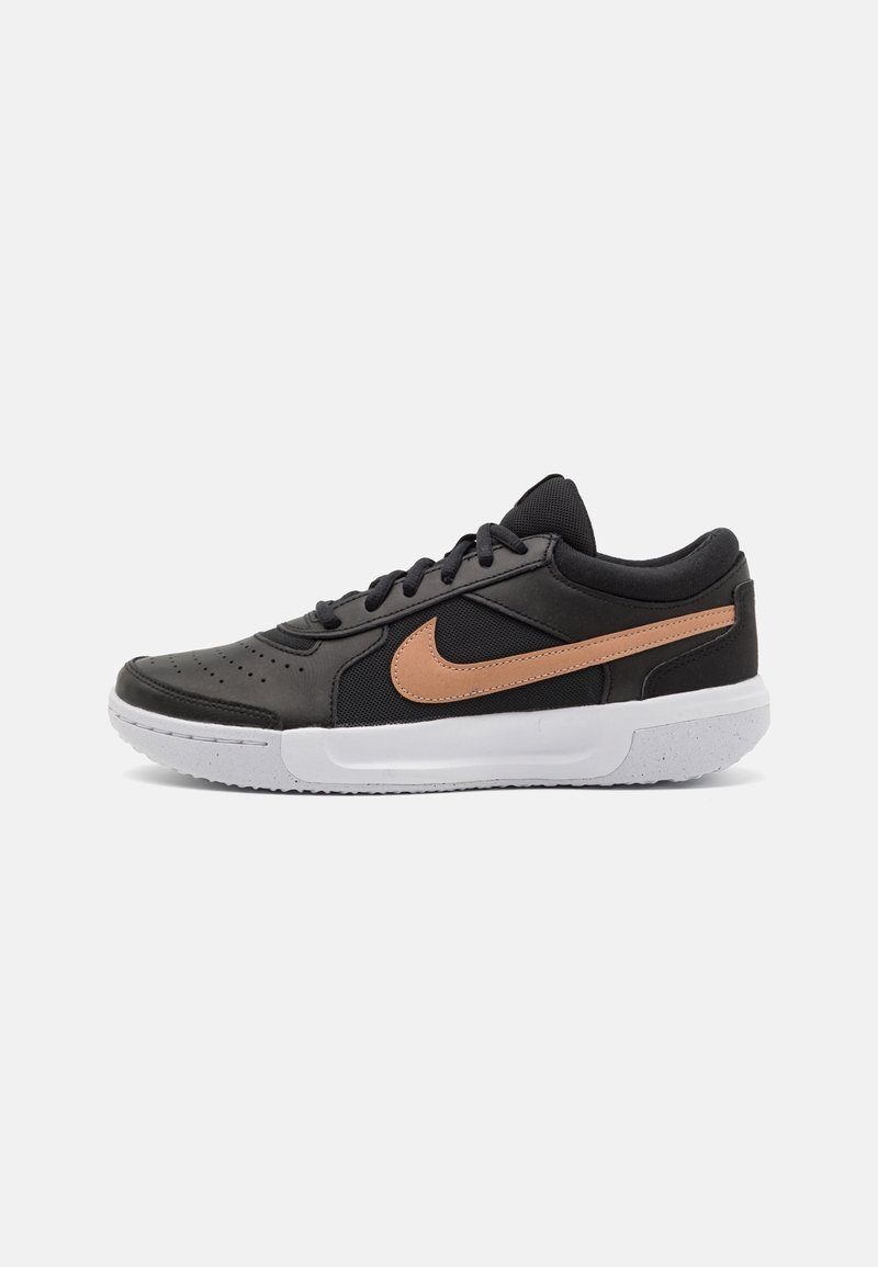 Scarpa sportiva nera realizzata in materiali in pelle e mesh, con una swoosh di accento marrone e una suola in gomma bianca. Parte superiore testurizzata con perforazioni.