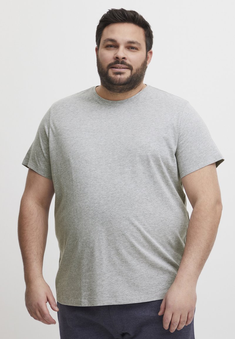 Tricou din bumbac gri, cu guler rotund și mâneci scurte, având o croială lejeră și o textură netedă. Purtați cu pantaloni bleumarin.