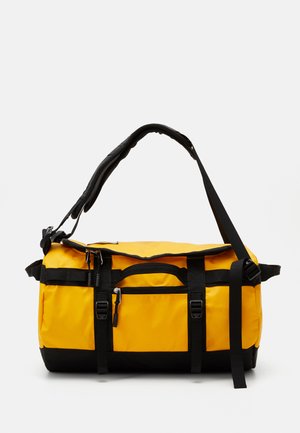 Yellow duffel bag with black accents, made of durable material. Features adjustable shoulder strap, multiple pockets, and clip closures.