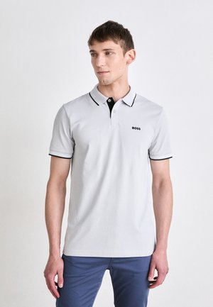 Polo shirt de manga corta en gris claro con cuello y acentos en las mangas negros, que presenta una tapeta con botones y un pequeño logo en el pecho.