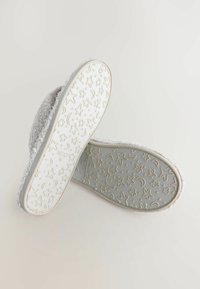 Sive puhasti copati z teksturirano podlago, ki ima vzorce zvezd in lune. Mehki material, zaobljena oblika in oblazinjena podplat.