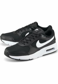Chaussures de sport noires en mesh et cuir, avec un logo Nike blanc, un col matelassé et un amorti à air visible dans la semelle.