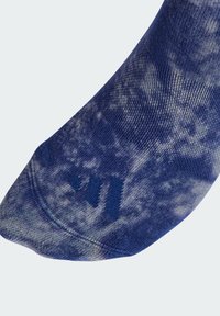 Blå tie-dye ankelstrømpe med en myk tekstur, med en logo i mørkeblå. Materialet er elastisk og sømløst på toppen.