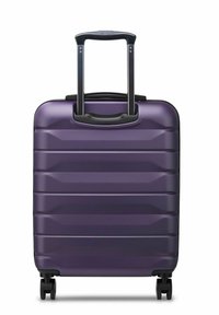 Maleta rígida morada con superficie texturizada, que cuenta con un mango telescópico y cuatro ruedas para una fácil maniobrabilidad.