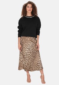 Czarna bluza z ozdobnym dekoltem, zestawiona z midi spódnicą w panterkę. Gładka faktura, zwiewny fason oraz sandały z paskiem wokół kostki.