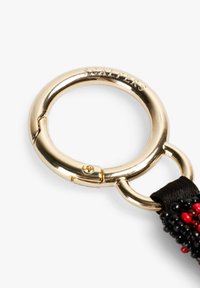 Llavero de metal dorado con un acabado liso y brillante, que cuenta con un cierre seguro y está unido a una correa de tela negra con cuentas rojas y negras.