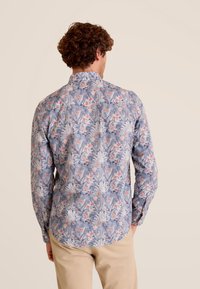 Langsleeve shirt met een blauw bloemenpatroon met roze accenten, gemaakt van lichte stof. Het heeft een standaard kraag en een gebogen zoom.