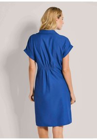 Blaues Kleid mit kurzen, umgeschlagenen Ärmeln, einem Kragen und einem eingereihten Taillengummi. Glatte Textur und knielanges Design. Schlichter und funktionaler Schnitt.