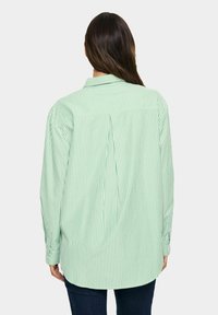 Camicia a righe verde e bianca con colletto classico e maniche lunghe, caratterizzata da una vestibilità comoda e orlo arrotondato.