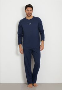 Navy blue long-sleeve shirt and matching pants made from soft cotton, featuring a discreet white "GUESS" logo on the chest.