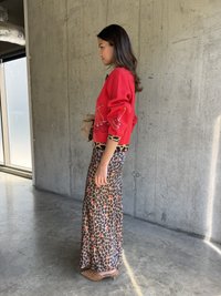 Sarkans kardigāns ar ķiršu rotājumiem, kombinēts ar leopardu raksta maxi svārkiem. Rāmi apavi ar auss, uz betona fona.