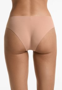 Nude seamless ondergoed met een gladde textuur, low-rise ontwerp en minimale bedekking, met een zachte elastische tailleband.