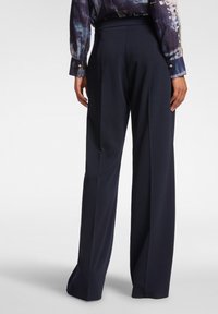 Marineblauwe wijde broek met een soepele textuur en subtiele plooien bij de taille, voorzien van een aansluitende tailleband en een losse pasvorm.