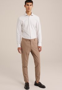 Fehér csíkos ing, bézs testre szabott nadrág, sötét cipő. Slim fit fazon gombos záródással és hosszú ujjakkal. Simább anyagtextúra.