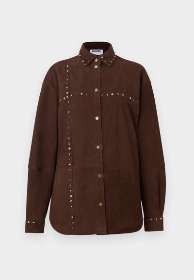 Καφέ πουκάμισο από σουέντ με μακριά μανίκια, μυτερό γιακά, χρυσά και ασημένια καρφιά κατά μήκος των ραφών, κουμπιά μπροστά και στα μανίκια, ετικέτα Moschino στο εσωτερικό του γιακά.