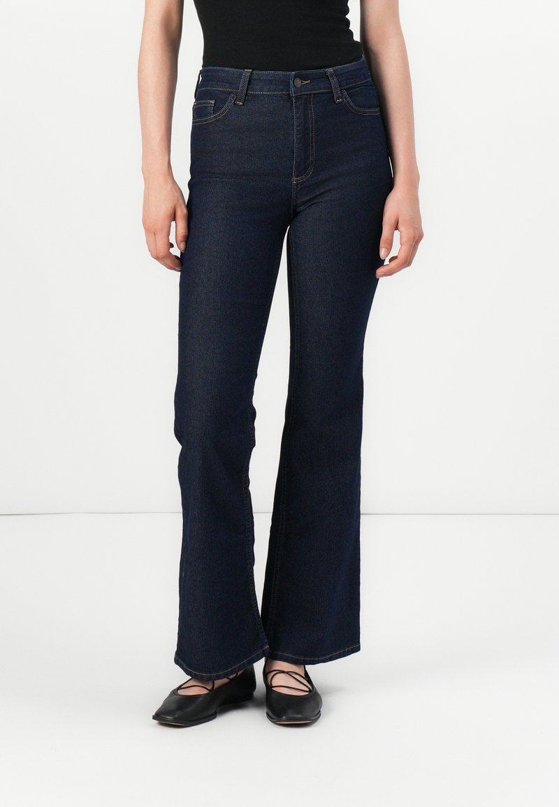 Dark blue flared jeans with a high waist, made of denim. Features a button closure, belt loops, and double-stitched seams.