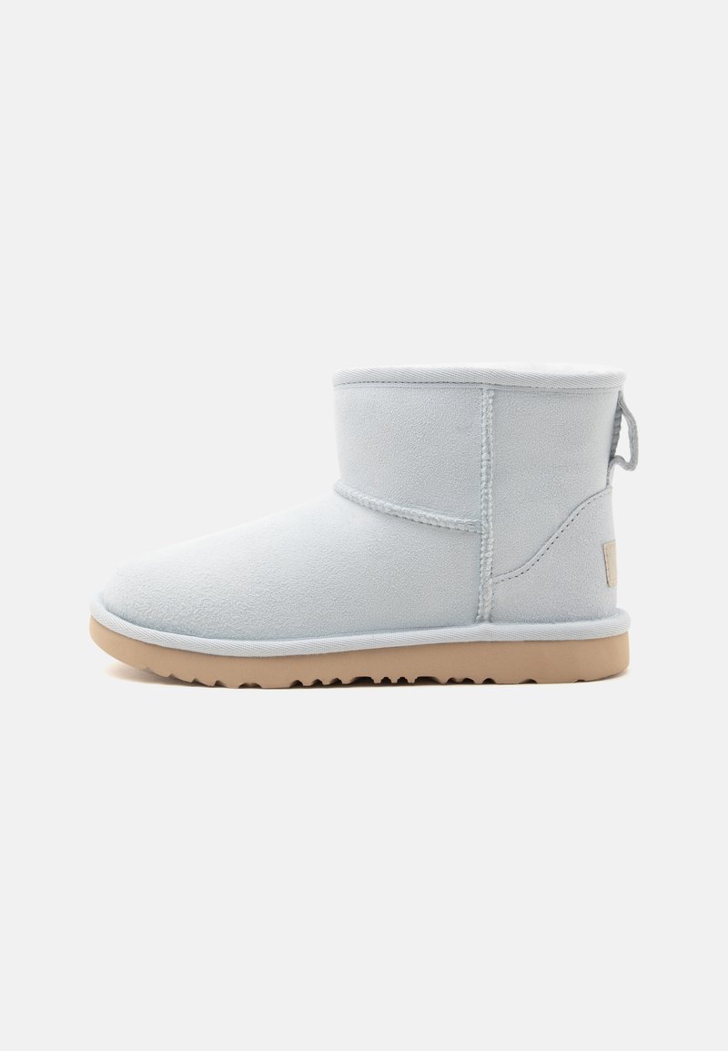 Bottine en daim gris clair avec semelle en caoutchouc beige et languette à l'arrière, montrée de profil sur un fond neutre.