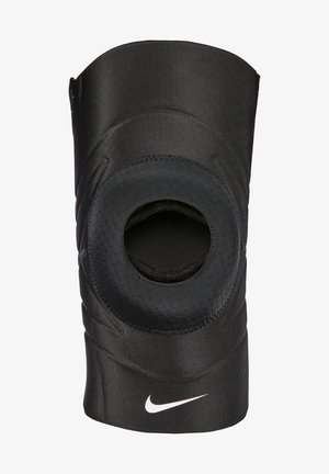 Svart knebeskytter laget av elastisk stoff med utklipp for knepatella, med teksturerte detaljer og en hvit Nike-logo.