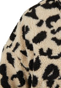 Beiger und schwarzer Leopardenmuster-Flauschstoff mit einer weichen, strukturierten Oberfläche, zeigt eine Nahaufnahme des Musters und der Textur des Materials.