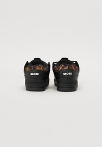 Black sneakers featuring a leopard print design on the heel, with a textured material and prominent white "GLOBE" logo on the sides.