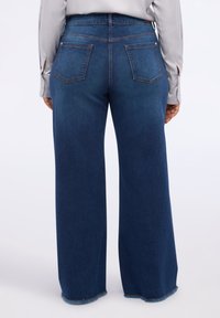 Džíny s širokými nohavicemi v tmavě modré barvě. Mezi funkce patří vysoký pas, dvě zadní kapsy a třepené lemy. Hladký povrch a pevná látka.