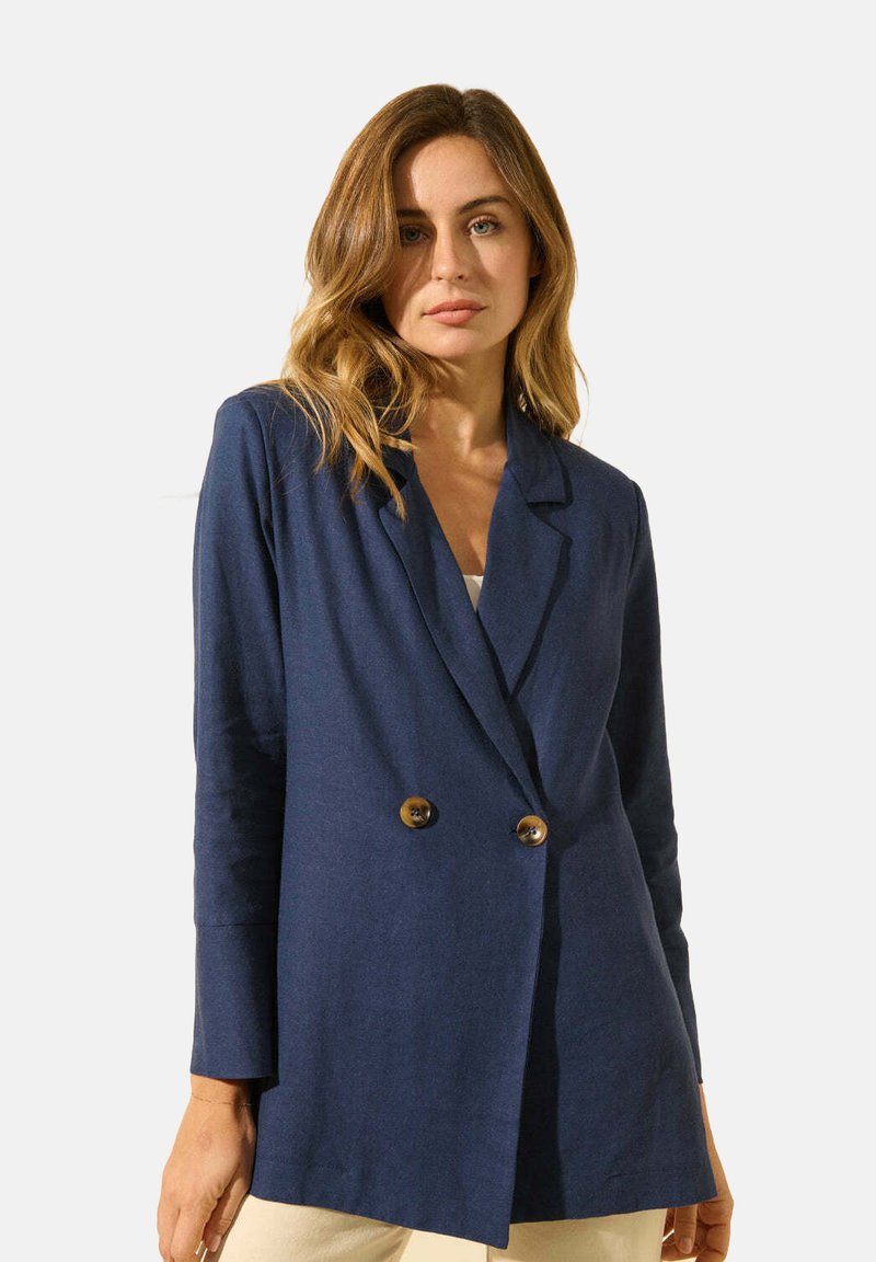 Blazer bleu marine à double boutonnage avec de grands boutons marron, revers à cran et manches longues, fabriqué à partir d'un tissu lisse au toucher doux.