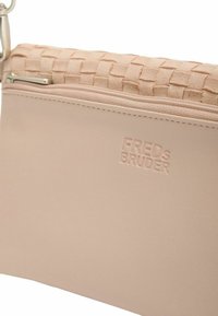 Borsa a tracolla beige con una texture intrecciata sulla parte superiore e una base in pelle liscia. Presenta una chiusura con zip e un logo del marchio impresso. Accent hardware in argento.