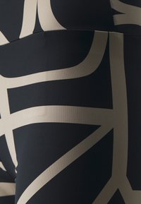Juodos aukšto liemens leginsai, dekoruoti dideliais abstrakčiais smėlio spalvos raštais. Lygus audinys su elastingumu patogumui ir tinkamumui.