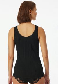 Schwarzes, geripptes Tanktop mit tiefem Rückenausschnitt, eng anliegendem Design und zarter Spitze am Saum, kombiniert mit passender schwarzer Unterwäsche.