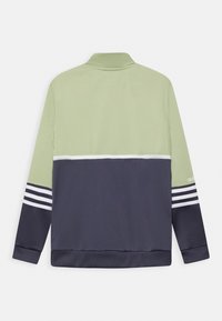 Bunda na zip v světle zelené a námořnické barvě. Měkká tkanina s vysokým límcem, bílými pruhy a žebrovanými manžetami. Stylový design s barevným blokováním.