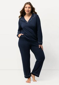 Set di pigiama blu scuro composto da una maglietta a maniche lunghe con piping bianco, colletto a punta e pantaloni abbinati con dettagli al fondo. Tessuto dalla superficie liscia.