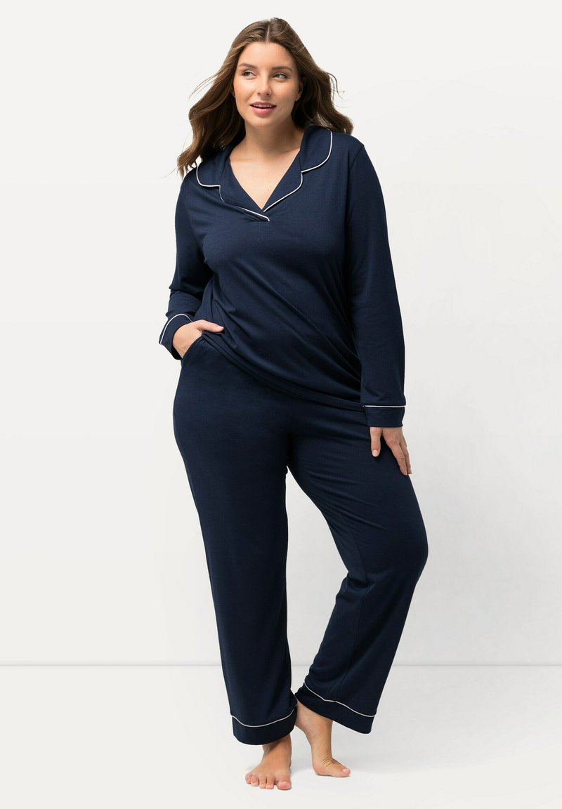 Set di pigiama blu scuro composto da una maglietta a maniche lunghe con piping bianco, colletto a punta e pantaloni abbinati con dettagli al fondo. Tessuto dalla superficie liscia.