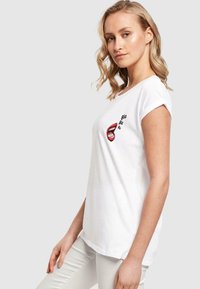 Hvid bomulds t-shirt med et grafisk motiv af røde læber og teksten "Bla Bla Bla." Korte ærmer med rullede opsmøg og en afslappet pasform.