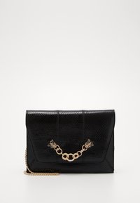 Sac à main en cuir noir texturé avec une bandoulière en chaîne, présentant un accent en métal doré et un design à rabat.