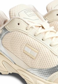 Beżowe i szare sneakersy Tommy Jeans o teksturowanej strukturze, z siateczkowego materiału, z sznurówkami z przodu oraz markowym logo po boku i na języku.