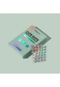Emballage holographique présentant "Cute Dots" pour les taches et imperfections. Contient des autocollants colorés en forme d'étoiles et de cœurs sur une feuille transparente.