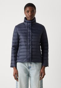 Marineblå dynejakke med vandret quiltet design, høj krave og blå knapper. Letvægtsmateriale med en glat, skinnende tekstur.