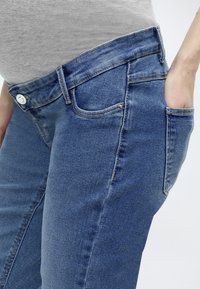 Τζιν παντελόνια από μεσαίο μπλε ύφασμα, στενή γραμμή, με πεντακάναλο σχέδιο, διαθέτουν κλείσιμο με κουμπί και φερμουάρ, καθώς και εμφανείς ραφές στις ραφές.