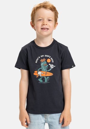 Camiseta negra con un gráfico de un cactus de dibujos animados con una tabla de surf, rodeado de texto y un sol en colores naranja y blanco.