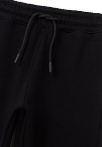 Schwarze Jogginghose mit elastischem Bund und verstellbarem Kordelzug. Glatte Stoffoberfläche und Seitenschlitze für optimale Bewegungsfreiheit.