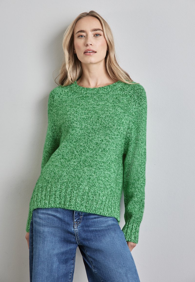 Grüner Strickpullover mit langen Ärmeln und geripptem Saum. Hat ein strukturiertes Finish und ein Rundhalsausschnitt-Design. Kombination mit blauen Jeans.