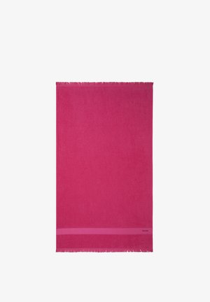 Serviette rectangulaire d'un rose vif uni avec des bords à franges et une bande étroite près d'une extrémité sur fond blanc.